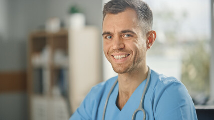 Portrait of Experienced Male Nurse Wearing Blue Uniform Smiling at Camera at Doctor's Office. Medical Health Care Professional Working On Battling Stereotypes to Gender Diversity in Nursing Career.
