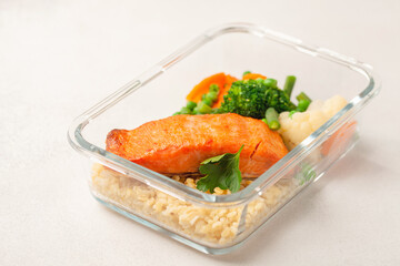 Salmon fillets with bulgur and vegetables in the container. Diet nutrition.