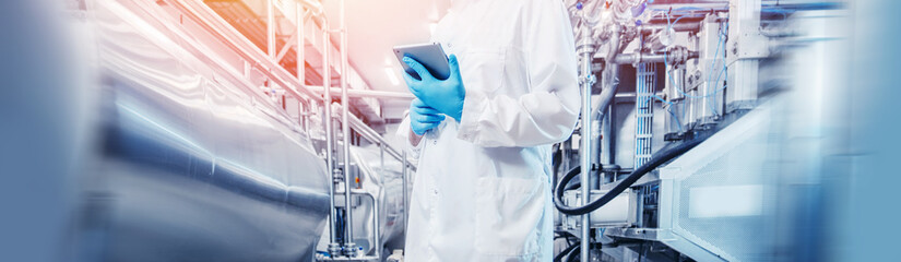 Concept industry food banner. Plant worker inspecting production line tanker in of beer or dairy factory with computer tablet