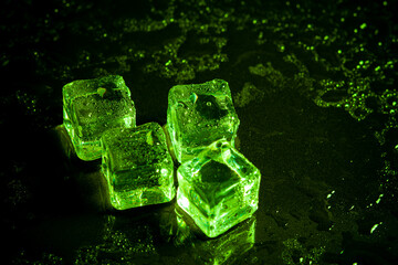 Green ice cubes reflection on black table background.