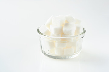 White sugar cubes in glass bowl isolated on white background. Selective focus.