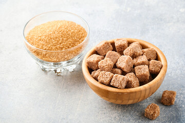 Cane sugar cube in bamboo bowl on gray table concrete background. Top view.