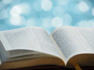 Open bible on sunlight with blue sea bokeh. Christianity, study bible, God word concept.