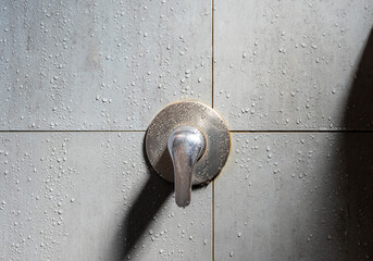 Close up water faucet with water drop on wall
