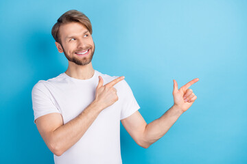 Photo of cheerful young man look direct two hands fingers empty space isolated on blue color...