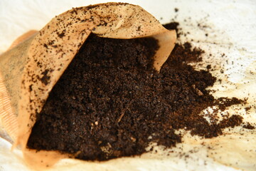 Kaffeesatz in Filtertüte mit grauem Hintergrund. Sie lieben es Kaffee zu trinken und es bleibt immer der Kaffeesatz übrig. Bitte nicht wegwerfen, kann als Dünger verwendet werden.