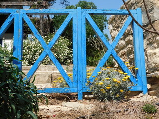 an old blue wooden fence in an abandoned garden. Protaras. Cyprus. April 2021