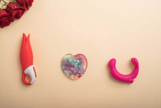 Flat lay of sex toys and a bouquet of roses on a cream background. Female masturbation addiction