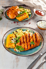 Grilled chicken breast with corn and zucchini on a blue plate top view. Summer dish with grilled chicken and vegetables on the white background vertical photo