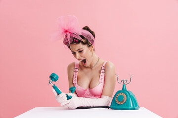 Woman screaming and talking on retro phone while sitting at table
