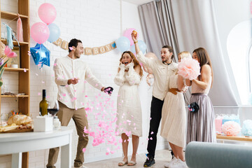 Excited couple blowing up surprise balloon during gender reveal party