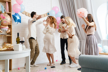 Couple with their friends laughing and dancing during gender reveal party