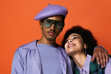trendy african american man in beret and sunglasses hugging happy woman isolated on orange