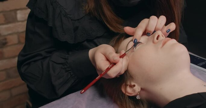 Lashmaker does the eyelash lamination procedure for the client in the beauty salon, cosmetic services, beauty care procedures, 4k 60p Prores HQ