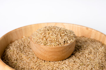 Raw brown rice in a bowl on white background. Selective focus.