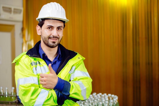 Portrait smart Latin worker in cargo port logistic warehouse standing confident thumbs up with safety suit.