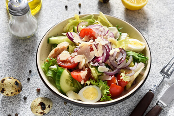 Vegetable salad and egg, chicken and parmesan on a concrete background. Green salad with cheese.