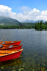 Obraz premium Lake Strbské pleso and a hotel in the High Tatras, Slovakia. Orange boats in front.