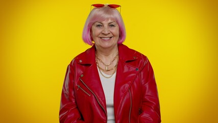 Cheerful lovely senior old woman rocker with pink hair in red leather jacket posing isolated on...