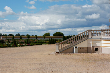 Fototapeta na wymiar Baroque staircase leading to the flower garden. Beautiful clouds in the blue sky