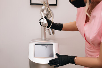 Beautician woman hands in black gloves. Beauty device laser CO2 fractional. Concept of rejuvenation...