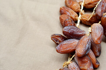 Dates (Phoenix dactylifera) on a wooden bowl on a brown cloth background. food for breaking the fast during Ramadan for Muslims. selective focus