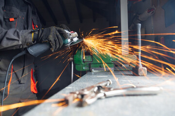 Worker using metal grinder in workshop creating sparks