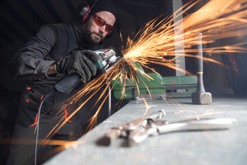 Worker using metal grinder in workshop creating sparks