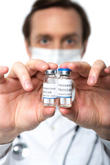 Coronavirus vaccine lettering on jars in hands of doctor in medical mask on blurred background isolated on white