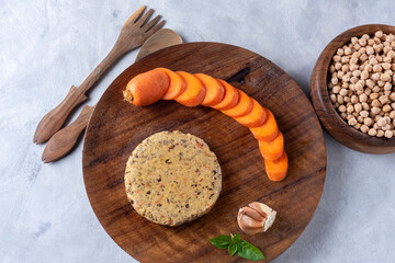Vegan and vegetarian burgers made of very healthy assorted legumes and fresh vegetables on a wooden plate and gray countertop.