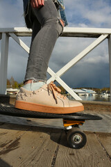 Close up of feet of a teenage girl in pink sneakers on a black skateboard. Sports, fitness lifestyle. City scene, city life