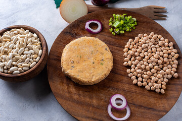 Vegan and vegetarian burgers made of very healthy assorted legumes and fresh vegetables on a wooden plate and gray countertop.