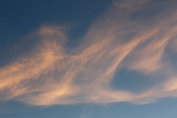 Blue sky clouds texture before sunset. Pink clouds of an unusual shape. Pattern and natural background