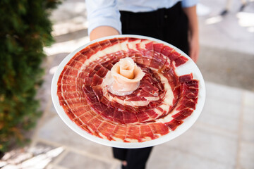 a waiter showing a plate of acorn-fed Iberian ham