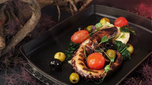 Octopus dishes with beautiful decor. Slow motion picture of food with smoke. Restaurant dish.
