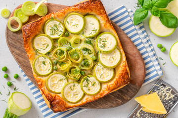Vegetarian vegetable pie. Tasty summer pie with zucchini, leek and peas on a light background top view.