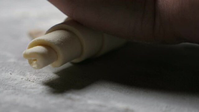 Female hands twisting up fresh dought in a larhe croissant at a bakery plant  