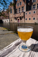 Tasting of Belgian beer on open cafe or bistro terrace with view on medieval houses and canals in Bruges, Belgium