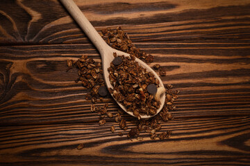 Chocolate granola cereal with nuts in a wooden spoon.