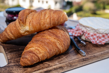Fototapeta premium French breakfast with fresh baked croissants and cheeses from Normandy, camembert and neufchatel served outdoor with nice city view