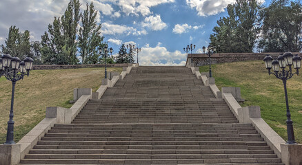 Stairway to Heaven .Bottom view of a wide stone pedestrian staircase in the city. Thick white-gray clouds are at the top. Growth and recovery concept. Empty staircase.