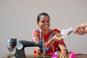 PORTRAIT OF A RURAL WOMAN using sewing machine and received counting money	