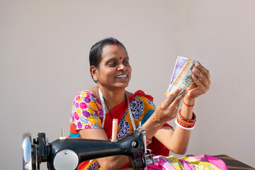 PORTRAIT OF A RURAL WOMAN using sewing machine and counting money	