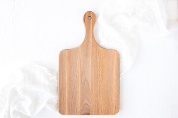 Wooden cutting board on white napkin and background, flat
