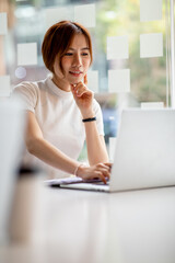 Image of young pleased happy cheerful cute beautiful business woman sit indoors in office using laptop computer,analyzing real estate investment data, Financial and tax systems concept.