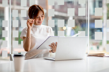 Image of young pleased happy cheerful cute beautiful business woman sit indoors in office using laptop computer,analyzing real estate investment data, Financial and tax systems concept.