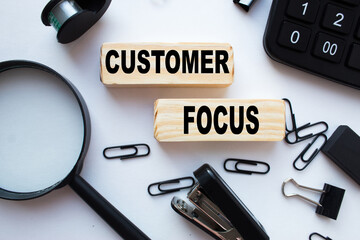 text CUSTOMER FOCUS on wooden cubes, with plants, coins, and stationery items. business concept