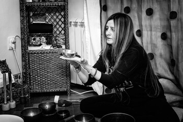 Woman playing a singing bowls also known as Tibetan Singing Bowls, Himalayan bowls. Tibetan Singing Bowls Treatment. Tibetan sound massage.