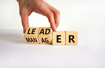 Manager versus leader symbol. Businessman turns wooden cubes and changes the word 'manager' to...