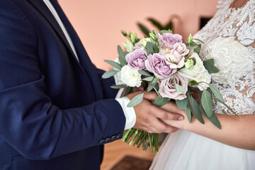 Obraz na płótnie Canvas Bride holding a wedding bouquet in the hands standing near groom